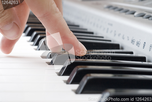 Image of hand playing music on the piano