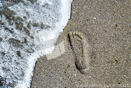 Image of sand stones with footprint and water wave