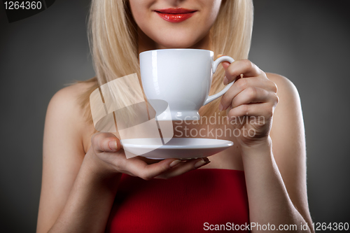 Image of woman in red holding cup and smiles