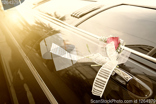 Image of Door of black wedding car with flower and ribbon