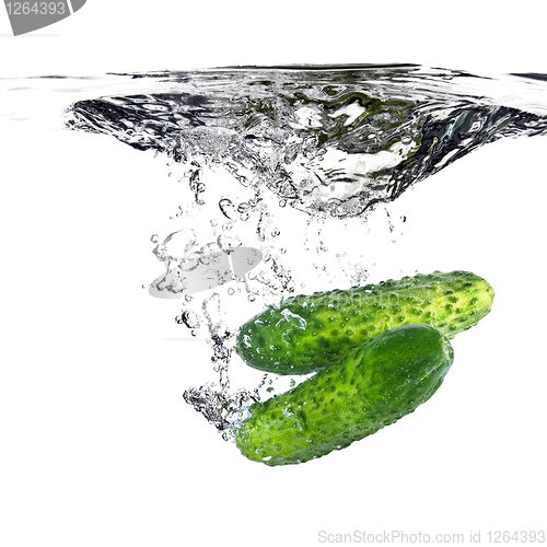 Image of green cucumbers dropped into water isolated on white