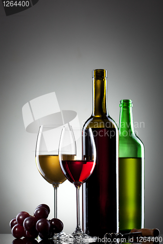 Image of Red and white wine in glasses with grape and bottles