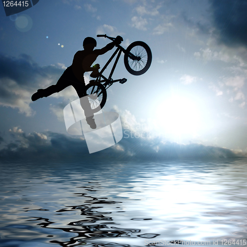 Image of silhouette of boy with bicycle jumping in air