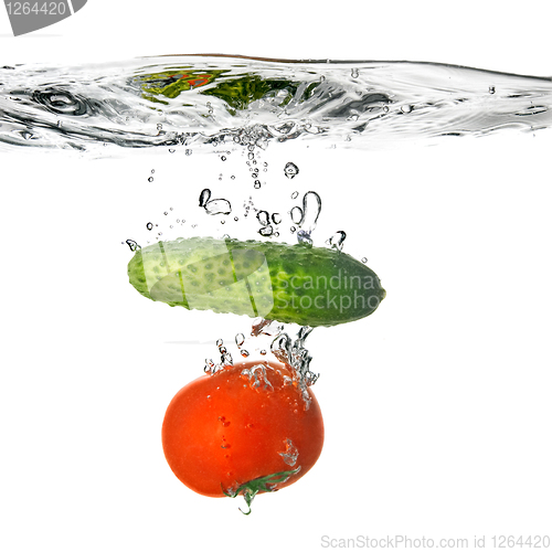 Image of tomato and cucumber dropped into water isolated on white