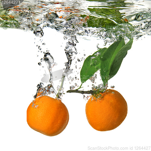 Image of tangerines dropped into water with bubbles on white