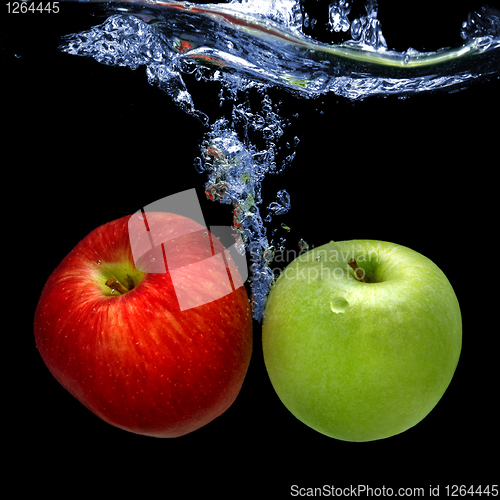 Image of apples dropped into water with splash isolated on black