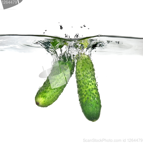 Image of two green cucumbers dropped into water isolated on white