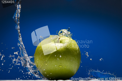 Image of Green apple with water splash on blue background