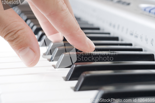 Image of hand playing music on the piano