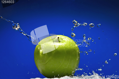 Image of Green apple with water splash on blue background