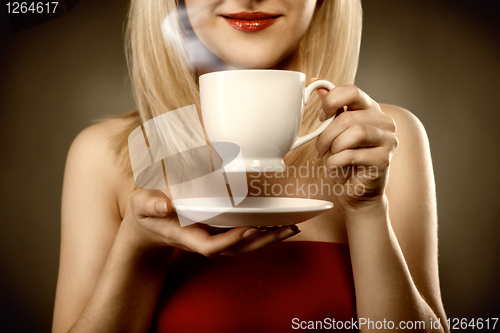 Image of woman in red holding cup and smiles