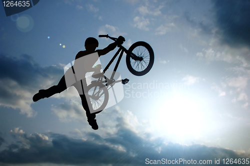Image of silhouette of boy with bicycle jumping in air