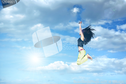 Image of girl jumping against blue sky and sun