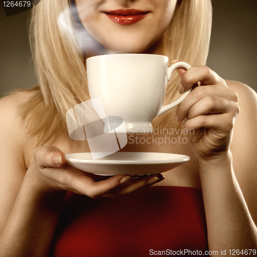 Image of woman in red holding cup and smiles