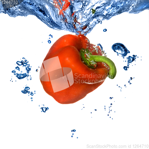 Image of Red pepper dropped into blue water with bubbles isolated on whit