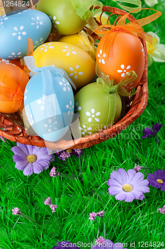 Image of color easter eggs in basket on the green grass