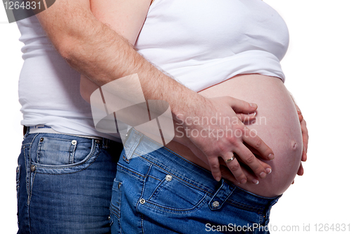 Image of Man and woman's hands over pregnant belly on white
