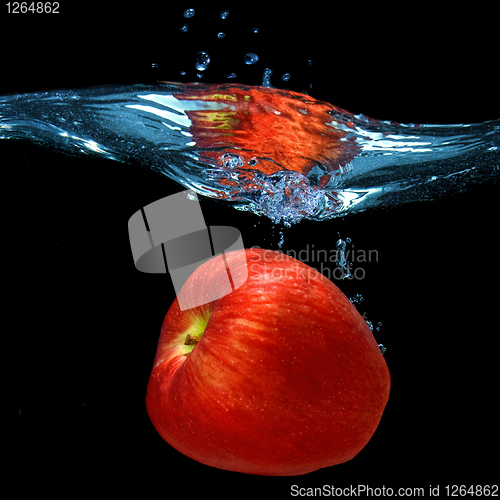 Image of red apple dropped into water with splash isolated on black