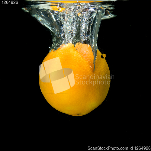 Image of orange dropped into water on black