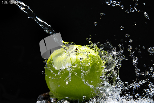 Image of Green apple with water splash on black background