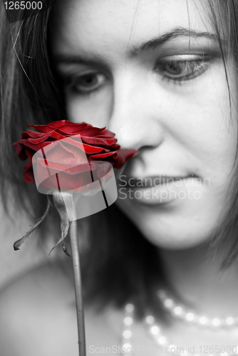 Image of black and white portrait of woman looking at red rose