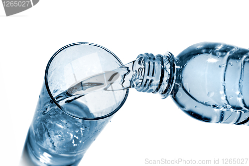 Image of water pouring into glass from bottle isolated on white