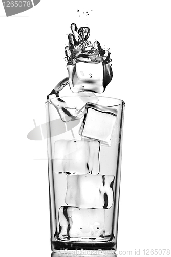Image of ice cubes dropped into glass with bubbles isolated on white