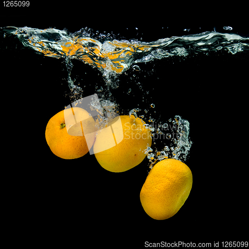 Image of Fresh tangerines dropped into water with bubbles on black