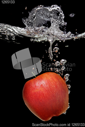 Image of green apple dropped into water with splash isolated on black