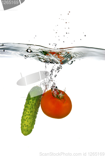 Image of red tomato and green cucumber dropped into water isolated on whi