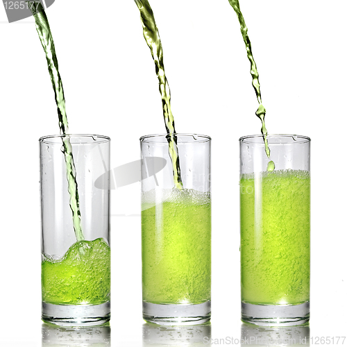 Image of green juice pouring into glass isolated on white