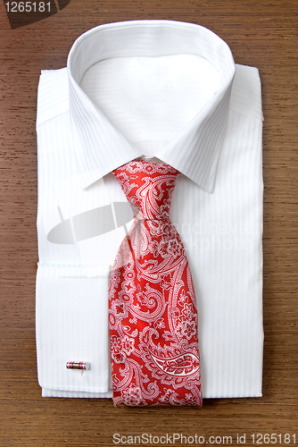 Image of white shirt with red tie on wooden shelf