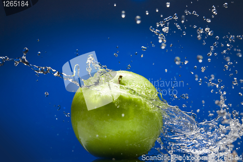 Image of Green apple with water splash on blue background