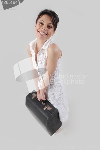 Image of Smiling brunette with travel bag in white dress