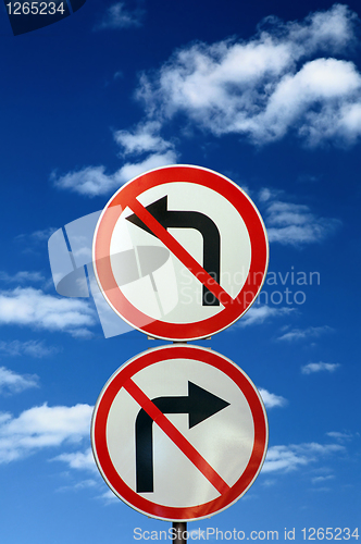 Image of two opposite road signs against blue sky and clouds
