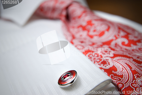 Image of close-up photo of stud on white shirt with red tie
