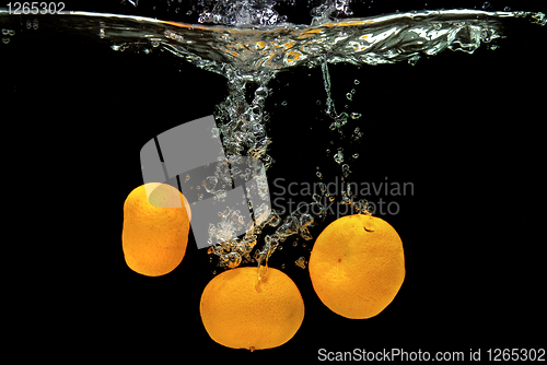 Image of Fresh tangerines dropped into water with bubbles on black