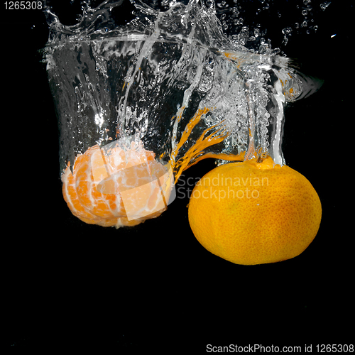 Image of Fresh tangerines dropped into water with bubbles on black