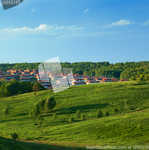 Image of Green meadow against blue sky and small town