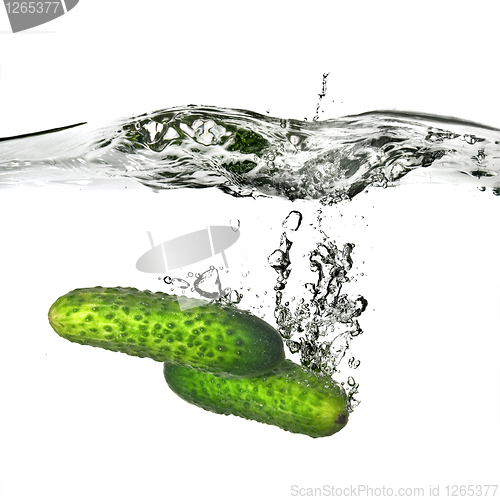 Image of two green cucumbers dropped into water isolated on white