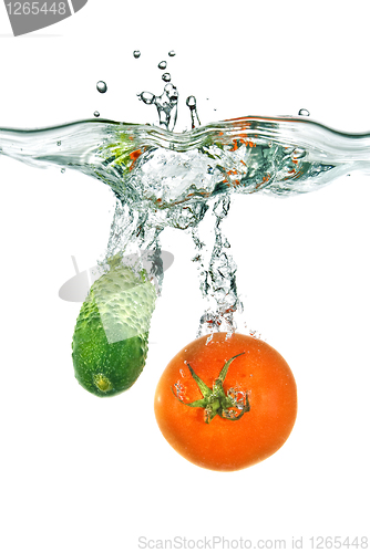 Image of red tomato and green cucumber dropped into water isolated on whi