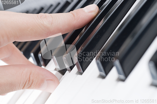 Image of hand playing music on the piano