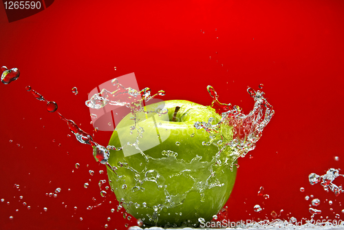 Image of Green apple with water splash on red background
