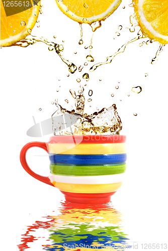 Image of Lemon juice and splash of tea in color cup with reflection