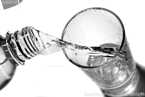 Image of water pouring into glass from bottle isolated on white