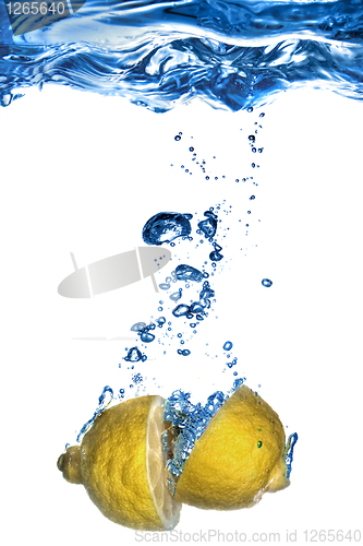 Image of Fresh lemon dropped into water with bubbles isolated on white