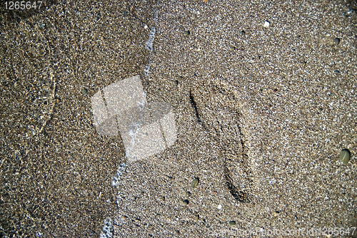 Image of sand stones with footprint and water wave