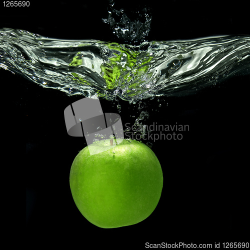 Image of green apple dropped into water with splash isolated on black