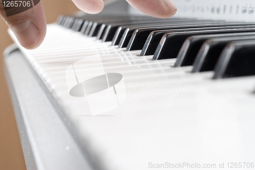 Image of hand playing music on the piano