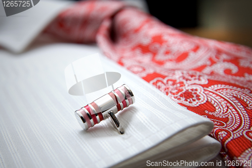 Image of close-up photo of stud on white shirt with red tie